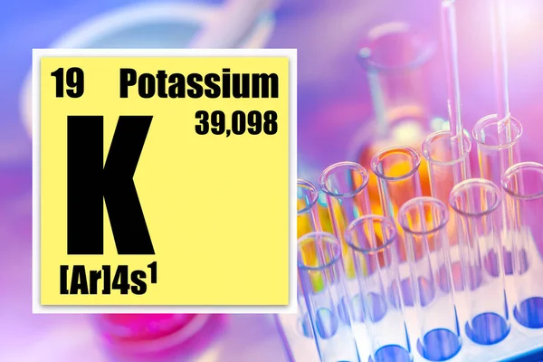 Potassium. Potassium logo from the periodic table. A cell from the periodic table next to test tubes. Concept - experiments with potassium. Fertilizer development. Laboratory tube rack.