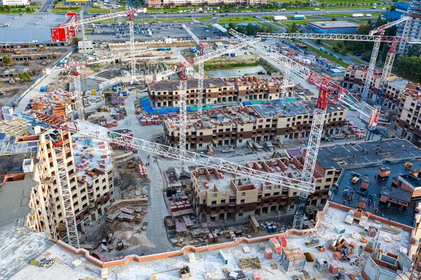 Construction site from a drone. Cranes and houses are being built. The concept of the construction. New city blocks. Sale of apartments in houses under construction. Primary real estate market.