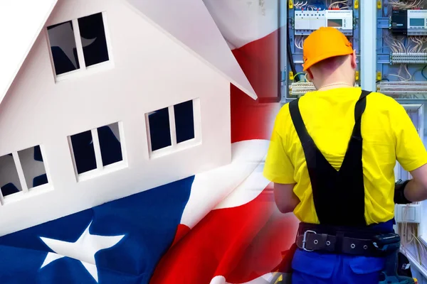 A man works with wiring on the background of a house with an American flag. Work as an electrician in the United States. Jobs for electricians in the United States. Wiring for a country house.