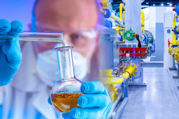 A man mixes chemical liquids against the background of chemical production. Chemical laboratory in the production. Quality control of raw materials. Product quality control.