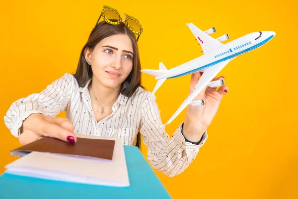 Girl dreams of traveling. Documents for the flight in the hands of a woman. Girl with an airplane toy in her hands. Student is playing with a model airplane. Concept - air travel. Holds out documents