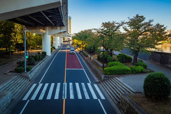 Japan. Cars go along the waterfront in Tokyo. The movement of vehicles in the Japanese capital. The railway bridge on supports is located above the highway. Transport system of Japan.
