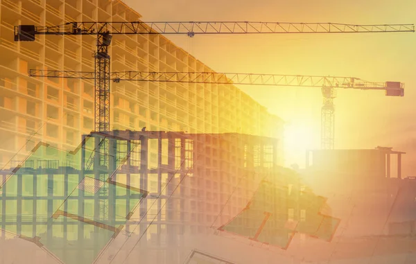 The concept of urban construction in yellow tones. Construction documentation, walls of future houses and cranes are illuminated by the sun. Construction of multi-storey buildings.