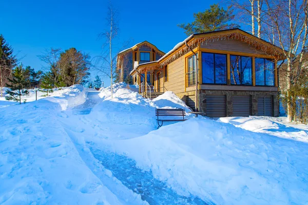 Sunny winter day in the village. Cottages with garlands in the background of the snowdrifts. Outdoor recreation in winter. Apartment. Houses in the cottage village. Winter holiday.