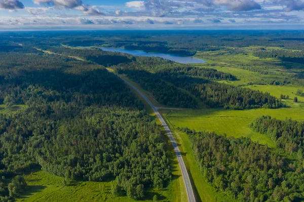 Top view of the road, forest and lake. A bird\'s-eye view of the landscape. The feeling of boundless space. Bird\'s-eye view of the road in the middle of forests and lakes.