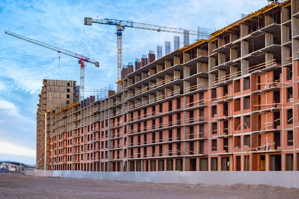 Buildings under construction on the background sky. Construction of panel houses. Concept - buying an apartment in a building under construction. Building crane during operation. Nobody