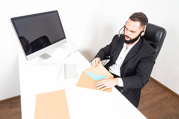 Business correspondence. Sending business papers. The man puts the documents in envelopes. A man with headphones at his Desk.