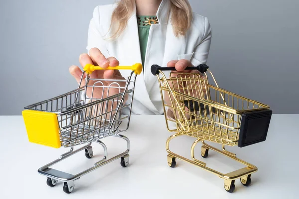 A woman next to two shopping carts. Consumer basket. Consumer behavior. Selecting the necessary purchases. The strategy of consumption. Purchases.