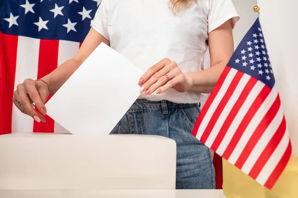 Election campaign in the United States. The girl puts the ballot in the basket for voting. An American woman votes in an election. Elections in the USA.