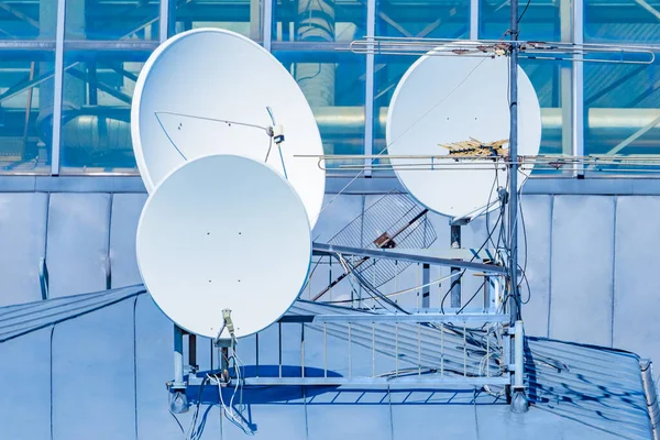 Satellite television antennas. Round satellite dishes on roof of the building. Several television antennas are installed nearby. Equipment for receiving tv signal. Concept - satellite television