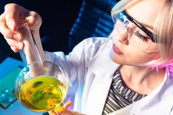 Woman laboratory technician. Lab assistant with a test tube close-up. Portrait of a laboratory technician holding a test tube. Laboratory technician examines test tube carefully. Lab employee career