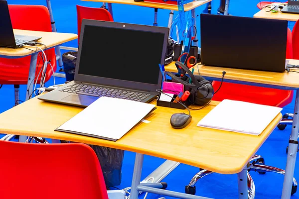 Computer class in College. Desks with laptops, headphones and stationery. New learning technologies. Online course. Training with the help of the Internet. Programming courses for students.
