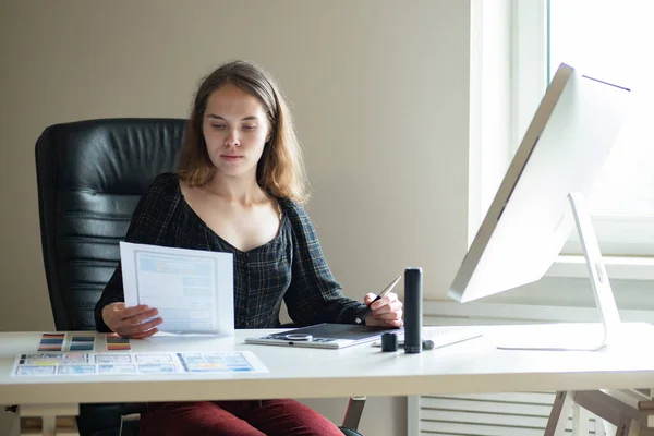 Application design. Mobile application designer at work. Girl at table draws a mockup of application for phone. UX designer creates a mockup of a mobile app. Designer uses a graphic tablet.