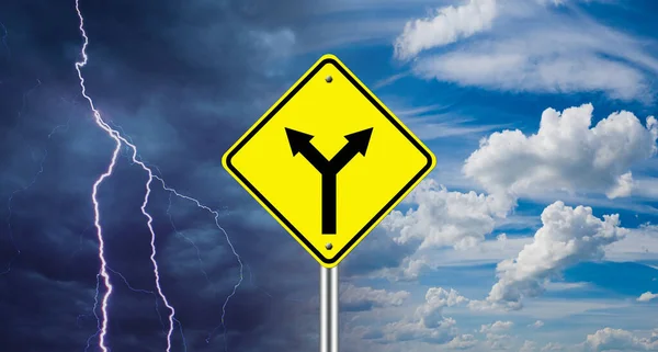 A road sign warns of a fork. The concept of choosing a path. The chosen road leads to different results. One arrow leads to a clear sky, the second to a hurricane.