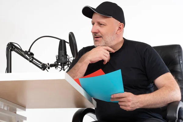 Radio presenter speaks into microphone. Man next to microphone on a white background. Adult man says something into a microphone. Concept - career as a radio host. Man working on radio.