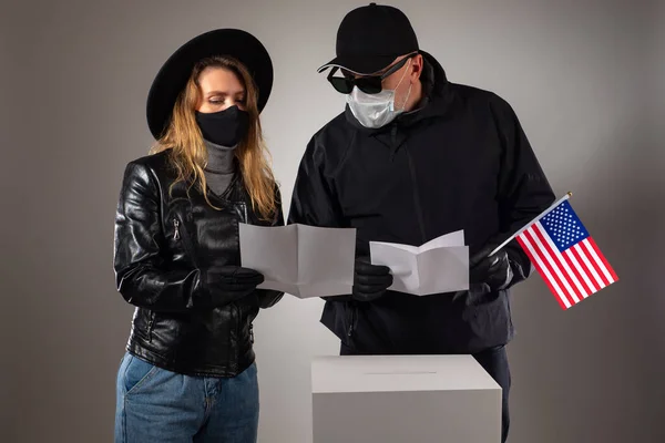 An American couple shares their voting choices with each other. A man and a woman wearing masks and rubber gloves at a polling station in the USA. Americans vote in the US Presidential election.