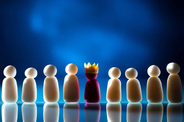The concept of a well-coordinated team. Collaboration under competent management. Little men stand in a row. One of the little men wears a crown. Metaphor - leadership in the team. Place for text.
