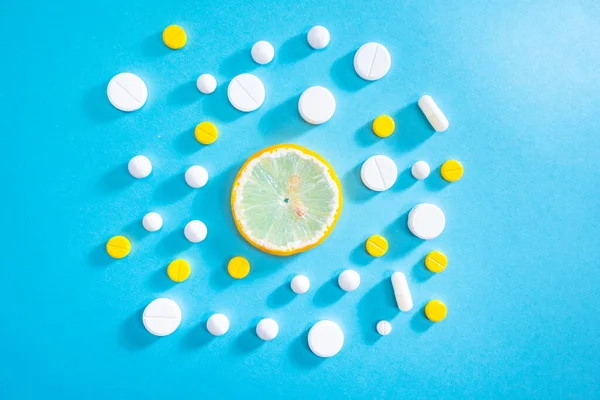 Vitamins. Prevention of beriberi. A slice of lemon surrounded by pills. The fight against vitamin deficiency. Care of health. The intake of vitamin preparations.