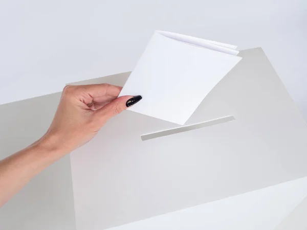 A woman hand drops the paper into a slot in the drawer. Voting in elections. Participation in the referendum. A woman with a ballot in the election. Opinion poll. Feedback from the buyers.