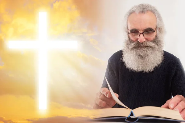 Symbol of Christianity. Man is reading bible. Elderly man with bible on sky background. Cross as a symbol of faith in Christianity. Christian cross glows in the sky. Concept - bible study.