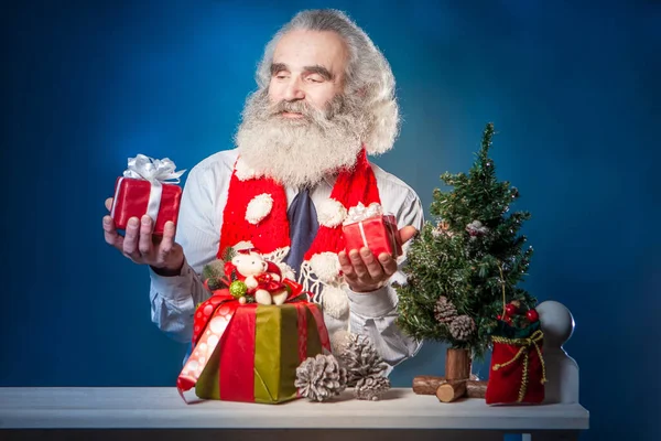 Grandfather with gifts for the New Year. Elderly man decorates the holiday Christmas. Gray beard. New Year. Gray-haired man. Grandpa is preparing presents. An elderly person rejoices at the holiday.