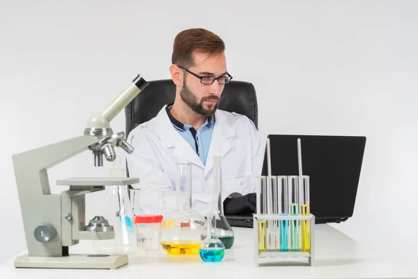 The chemist enters the results of the experiment into the computer. A man works on a laptop in the chemical laboratory. The course of the experiment with chemical liquids.