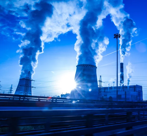 View of a working factory,  the smoke rush from chimneys on sunset