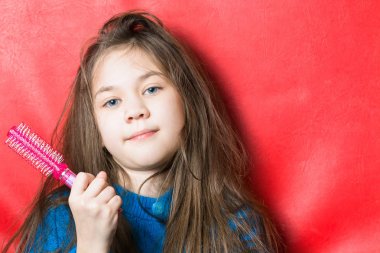 Mavi ceketli güzel kız elinde kırmızı bir arka plan üzerinde bir tarak tutar