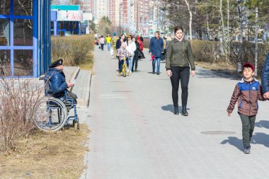 Surgut, Rusya - 9 Mayıs 2018: Arabada bere savurarak askeri engelli kişi yoldan geçenlerden para istiyor. Tatil Zafer Bayramı 9 Mayıs.