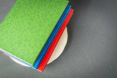 Renkli kitap yığını beyaz bir tabak üzerinde yatıyor