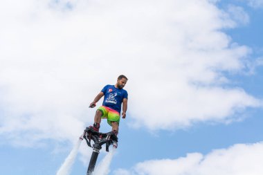 Side, Türkiye - 1 Haziran 2018: Yakışıklı tabaklanmış adam sineklikte duruyor ve bulutlarla mavi gökyüzüne uçuyor.