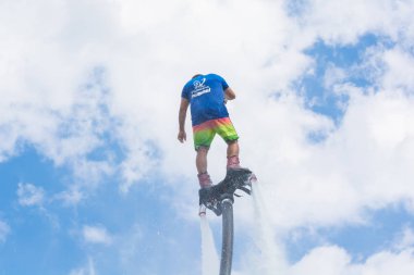 Side, Türkiye - 1 Haziran 2018: Yakışıklı tabaklanmış adam sineklikte duruyor ve bulutlarla mavi gökyüzüne uçuyor.