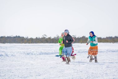 Russkinskaya, Rusya - 24 Mart 2018: Ulusal kuzey giyimli hanlı kadınlar kışın çapraz koşuyor. Kızlar arasındaki rekabet. Reindeer çobanları günü bayramı.