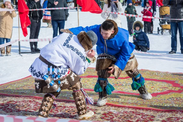 ラスキンスカヤ、ロシア - 24 3月 2018: 国家シベリアの服を着た2人の経験豊富な男性は、中央広場で、公共の場で男性のレスリングに従事しています。闘争の賭けのための競争 — ストック写真