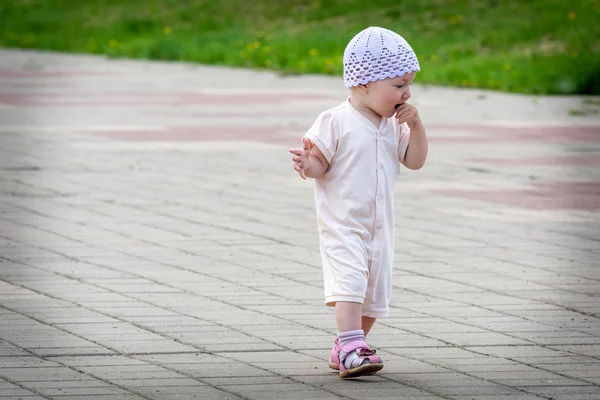 Un niño pequeño en un traje blanco que corre alrededor del camino pavimentado desde el muelle del puerto del río — Foto de Stock