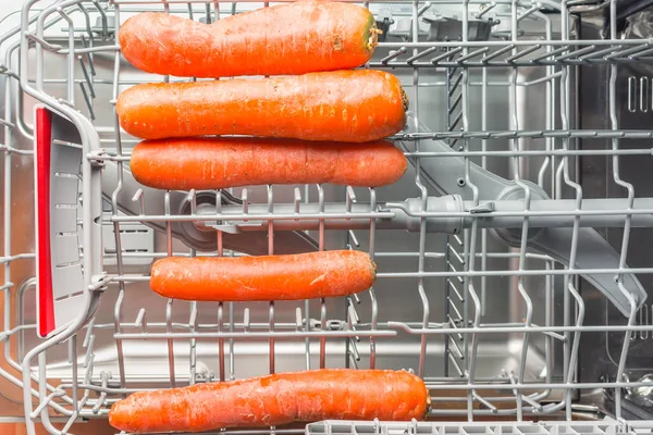 Длинная морковь лежит в посудомоечной машине — стоковое фото