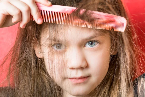 Sweet girl is combing a bang on a red background — Stock Photo, Image