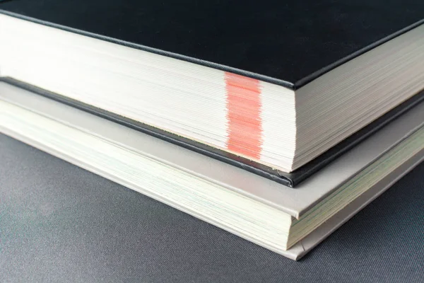 Livro grosso preto repousa sobre um livro cinza — Fotografia de Stock