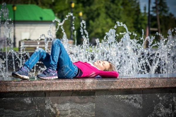 Щаслива дитина лежить біля фонтану в парку — стокове фото