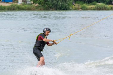 Krasnodar, Rusya - 7 Haziran 2018: Kasklı atletik adam su tutma ipinin üzerine biniyor.