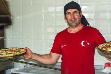 Side, Turkey - 1 Haziran 2018: Elinde pizzalarla kırmızı ayakkabılı bir Türk şefin portresi.