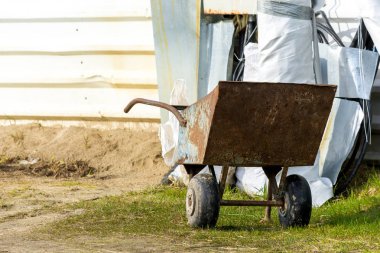 Tekerlekler üzerinde paslı demir sepeti.
