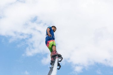 Side, Türkiye - 1 Haziran 2018: Yakışıklı tabaklanmış adam sineklikte duruyor ve bulutlarla mavi gökyüzüne uçuyor.