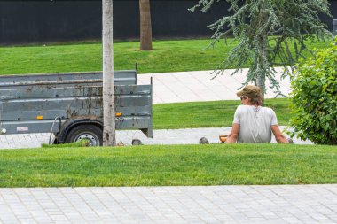 Krasnodar, Rusya - 7 Haziran 2018: Şapkalı işçi römorkun yanında çimlerin üzerinde.