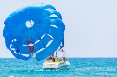 Side, Türkiye - 31 Mayıs 2018: Mavi denizde hızla giden teknenin hızından turistlerle mavi paraşüt gökyüzüne yükseliyor.