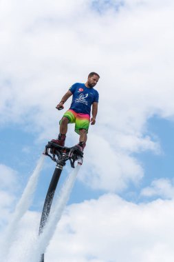 Side, Türkiye - 1 Haziran 2018: Yakışıklı tabaklanmış adam sineklikte duruyor ve bulutlarla mavi gökyüzüne uçuyor.