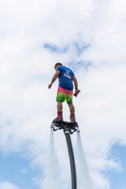 Side, Türkiye - 1 Haziran 2018: Yakışıklı tabaklanmış adam sineklikte duruyor ve bulutlarla mavi gökyüzüne uçuyor.