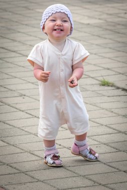 Nehir limanının rıhtımından asfalt yolun etrafında koşan beyaz takım elbiseli küçük bir çocuk.