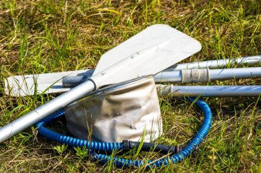 Pompanın yanındaki çimenlerin üzerinde yatan kesedeki kürekler.