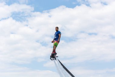 Side, Türkiye - 1 Haziran 2018: Yakışıklı tabaklanmış adam sineklikte duruyor ve bulutlarla mavi gökyüzüne uçuyor.